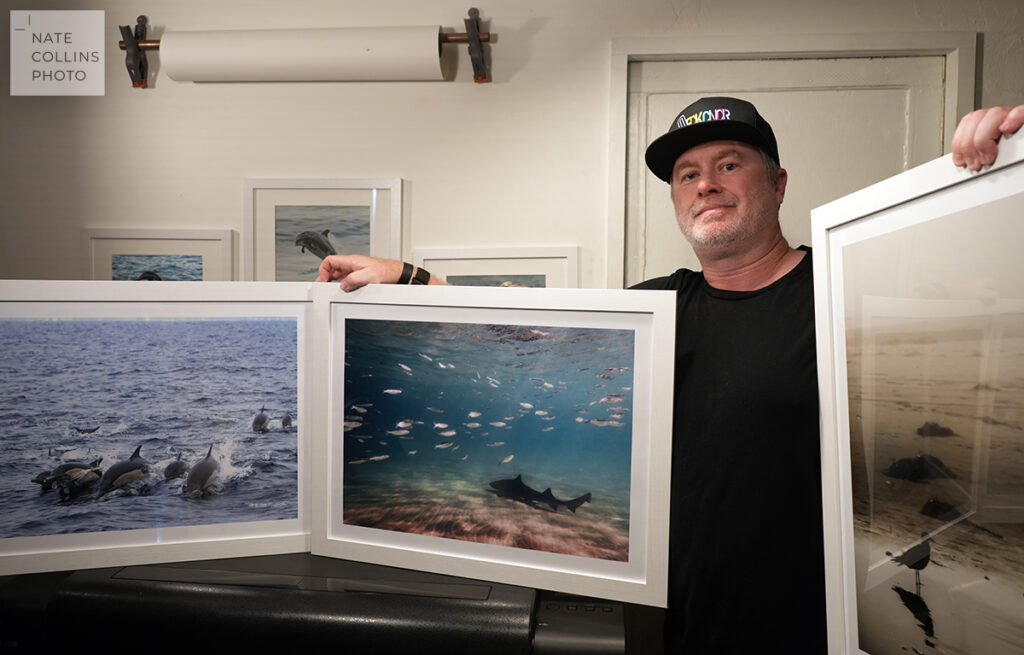 Nate Collins from Nate Collins Photo holding three large prints in the print office.